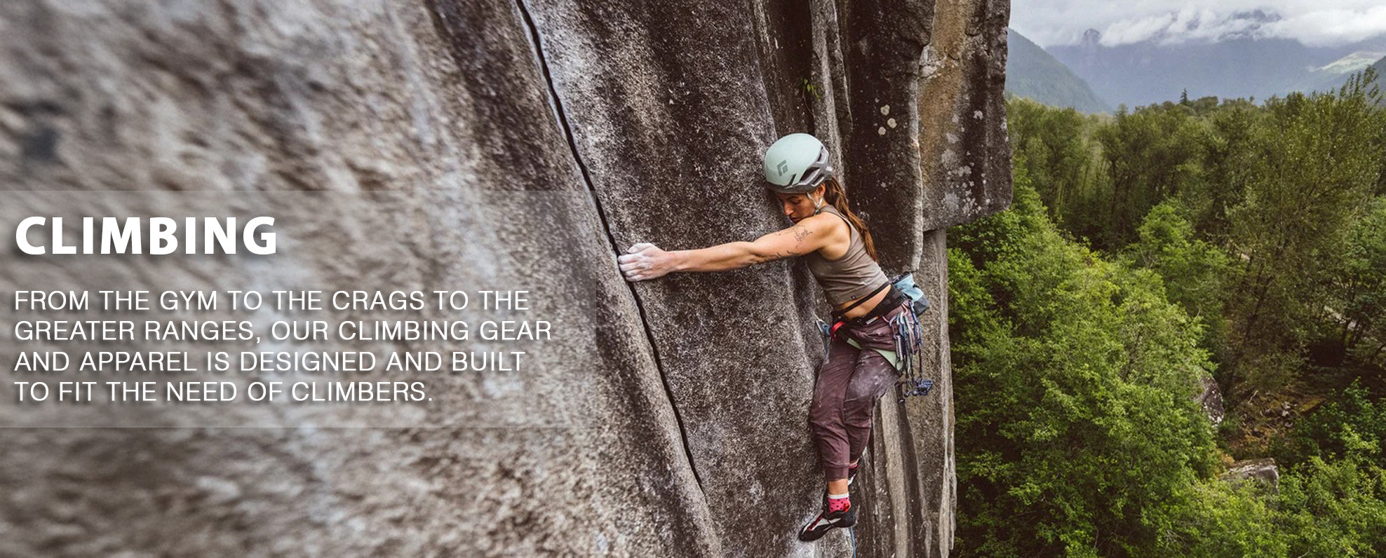 Person climbing a rock wall wearing climbing gear.